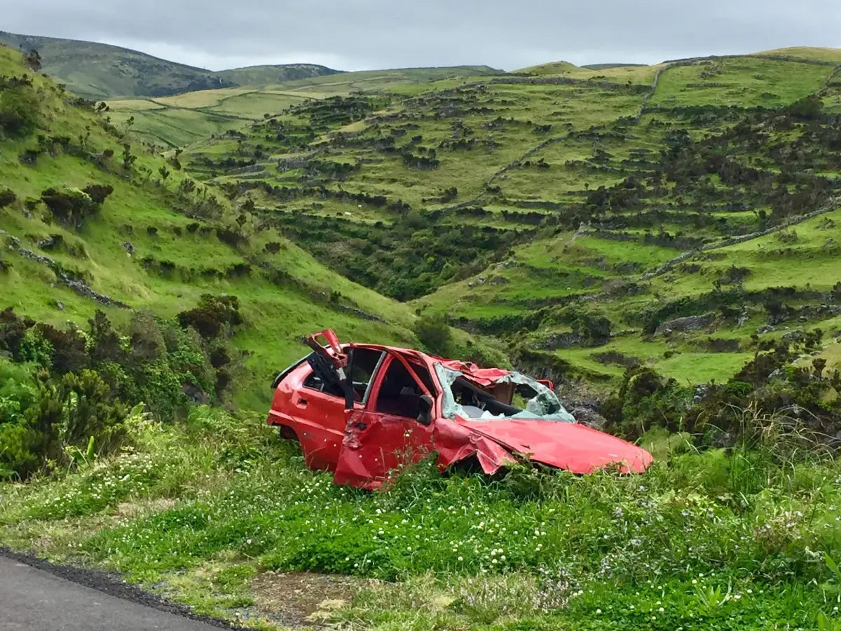 Red scrap car dumped by road